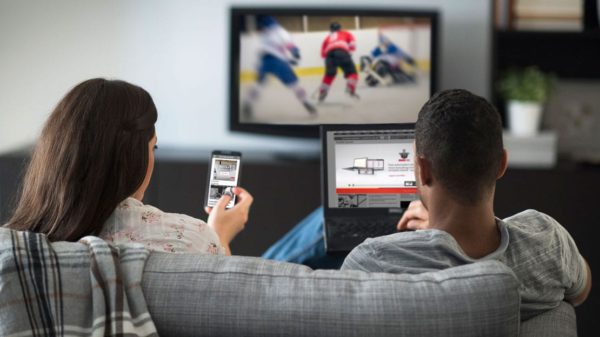 Man and woman using smartphone and tablet watching TV